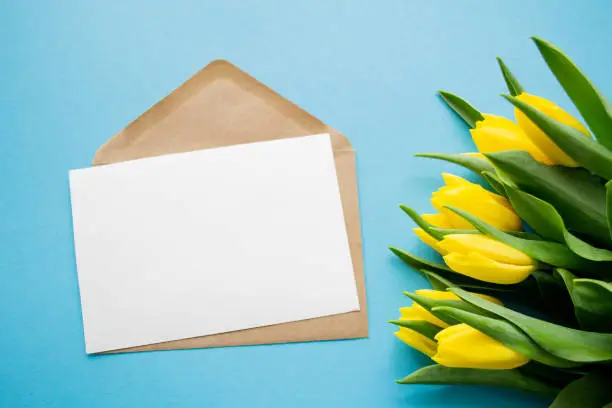 Photo of Paper letter envelope postcard, yellow tulips. Copy space