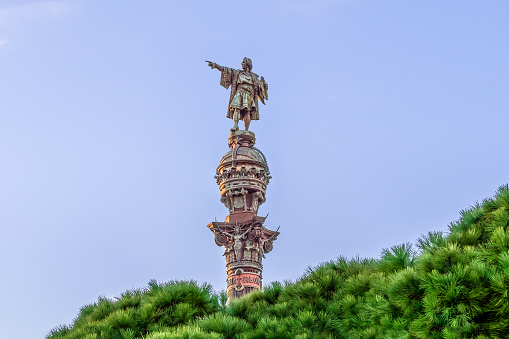 Barcelona, Spain - November 26, 2021: Monument a Colom in Barcelona, close-up. Statue of Christopher Columbus on top of Corinthian column, isolated on a blue sky. Author: Gaieta Buigas i Monrava, 1888