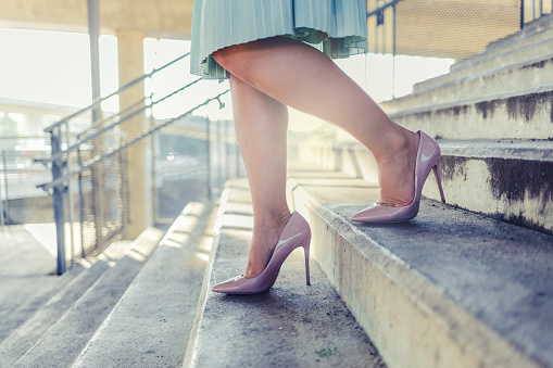 Close up photo of businesswoman legs walking up marble stairs with bag in her hand