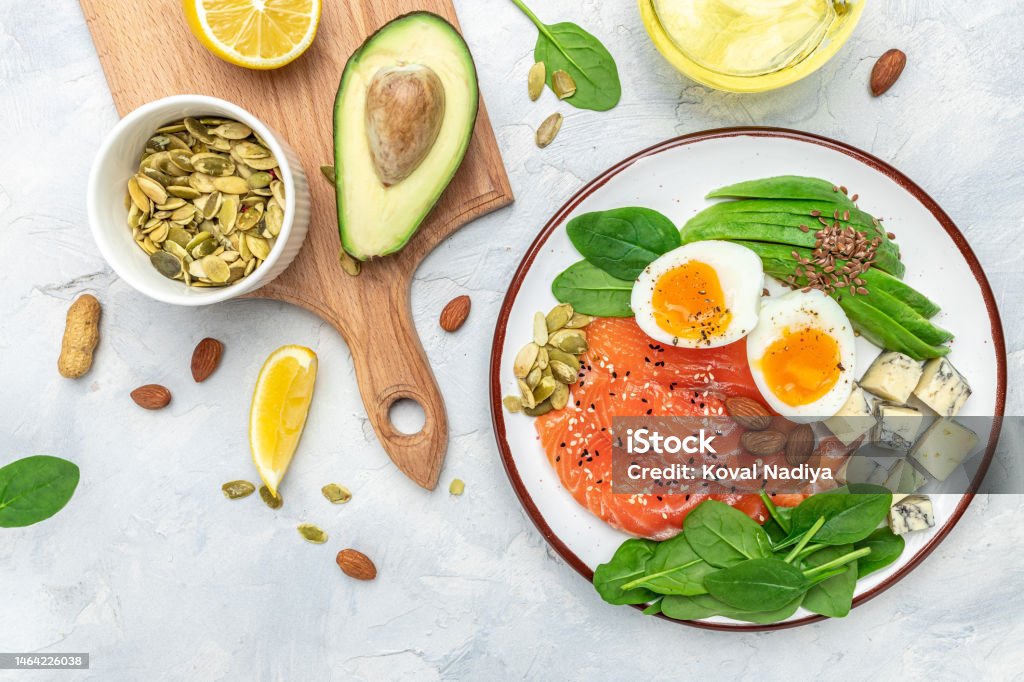 Set of diet food, salmon, avocado, cheese, egg, spinach and nuts on a light background. banner, menu, recipe place for text, top view Set of diet food, salmon, avocado, cheese, egg, spinach and nuts on a light background. banner, menu, recipe place for text, top view. Healthy Eating Stock Photo