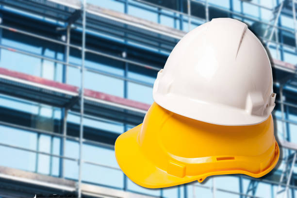 istock Yellow and white protection helmets isolated on white. Construction site. Head safety.Scaffolding background. 1464229486