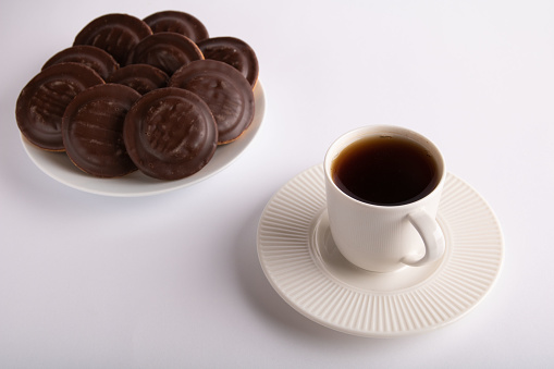 photo chocolate chip cookies on a white plate and a coffee cup with a drink on a white background
