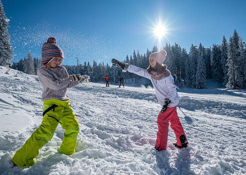Children throw snowballs at each other in the ski area next to the track.