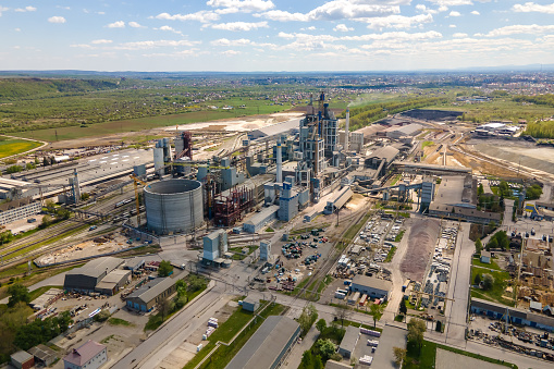 Aerial view of cement plant with high concrete factory structure and tower crane at industrial production area. Manufacture and global industry concept.