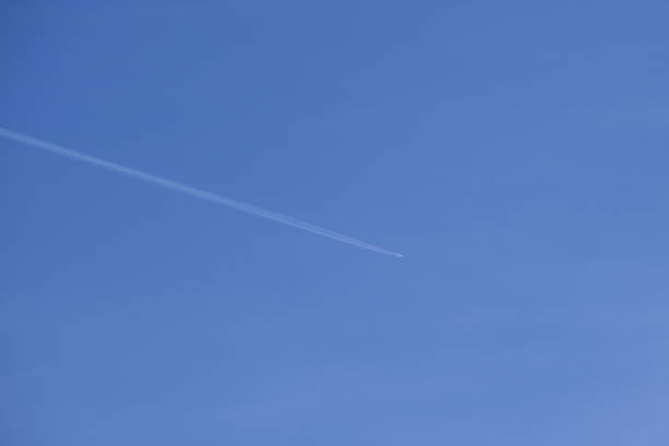 istock Distant passenger jet plane flying on high altitude on clear blue sky leaving white smoke trace of contrail behind. Air transportation concept. 1464236307