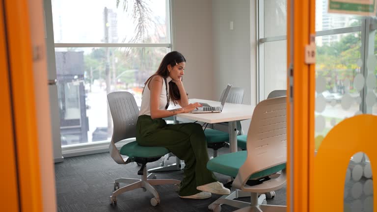 Young woman using the laptop and the mobile phone in the office