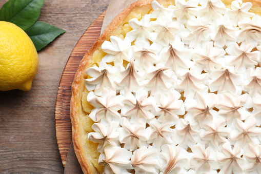 Homemade layered vanilla cake with meringue on a plate on a dark table