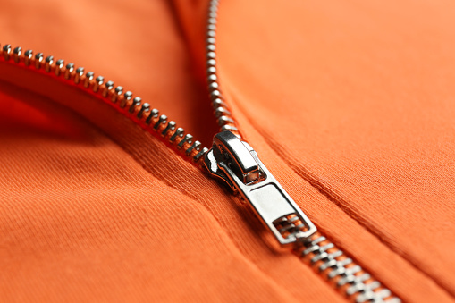 Orange sweatshirt with zipper as background, closeup view
