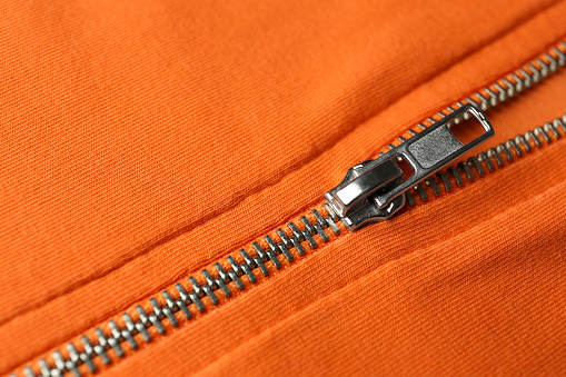 Orange sweatshirt with zipper as background, closeup view