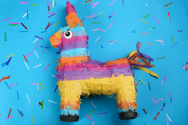Bright donkey pinata and confetti on light blue background, flat lay