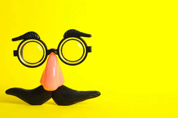 Funny face made with clown's accessories on yellow background, space for text