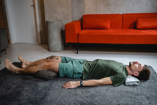 One modern caucasian man adult male practice restorative yoga at home