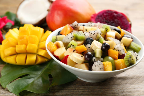 istock Delicious exotic fruit salad and ingredients on wooden table 1464240281