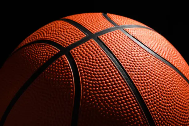 Photo of Orange basketball ball on black background, closeup