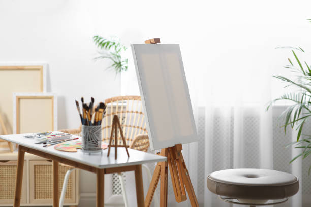 istock Table with paints and tools near easel in art studio 1464240472