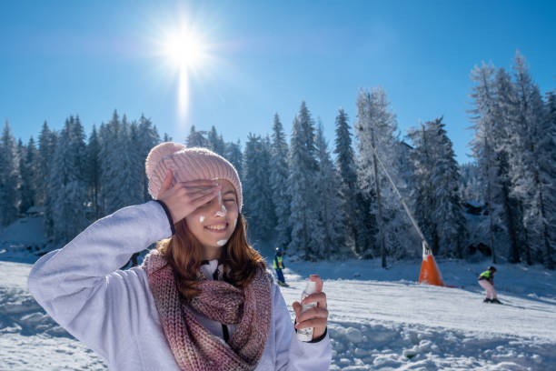 A teenage girl applies sunscreen on a ski resort. stock photo