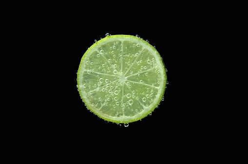 Slice of lime in sparkling water on black background. Citrus soda