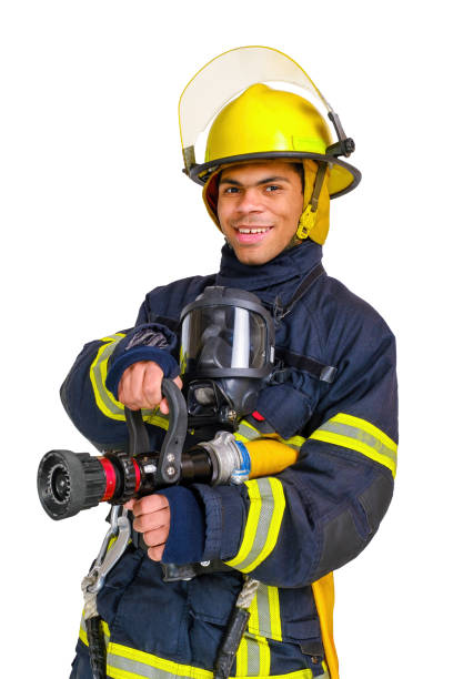 un pompier en uniforme et casque tient un tuyau d’incendie dans les mains - black and white military uniform headwear one person photos et images de collection