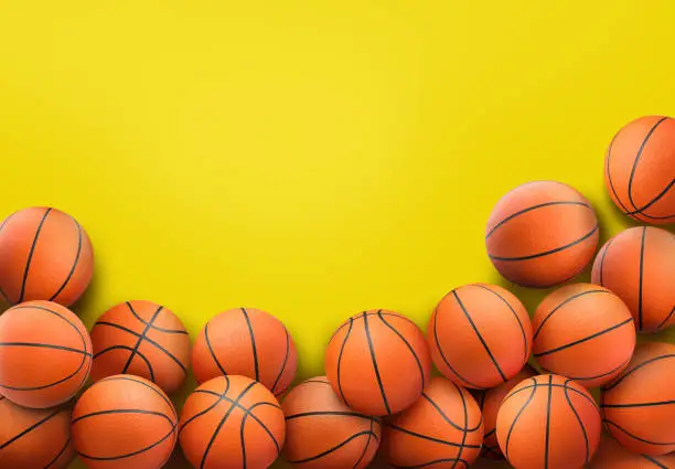 Photo of Many orange basketball balls on yellow background. Space for text