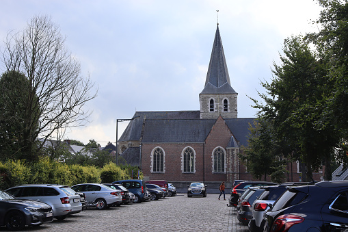 Laarne, Belgium, 11 September 2022: View of the parish church of Laarne and parking area in the village centre. Laarne is a tourist destination in Flanders with a famous 12th century castle.