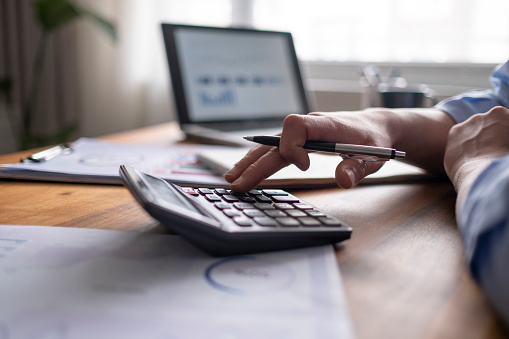 Concepto de contabilidad de negocios, Hombre de negocios usando calculadora con computadora portátil, presupuesto y papel de préstamo en el cargo. photo
