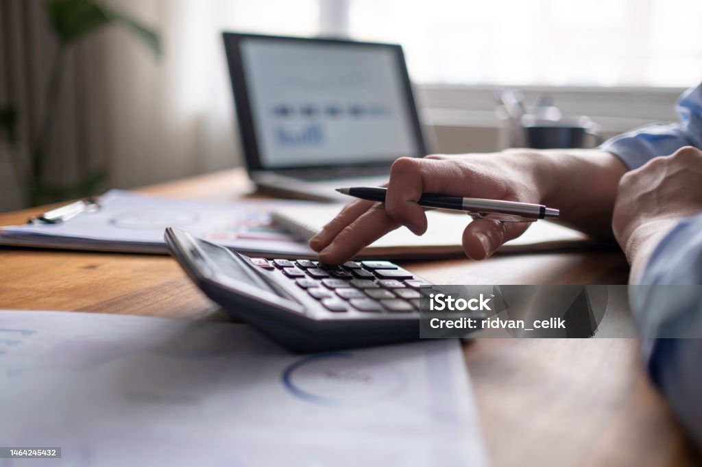 Business accounting concept, Business man using calculator with computer laptop, budget and loan paper in office. Calculator Stock Photo