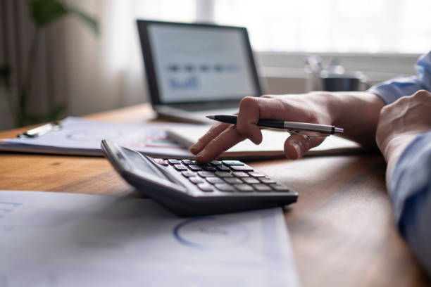 koncepcja rachunkowości biznesowej, człowiek biznesu za pomocą kalkulatora z laptopem komputerowym, budżet i papier pożyczkowy w biurze. - kalkulator zdjęcia i obrazy z banku zdjęć