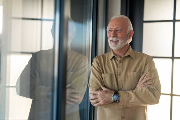 istock Gray haired senior man daydreaming and looking through window 1464249489