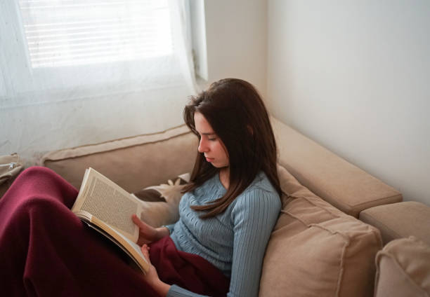 istock Young student reading a book in her living room. 1464250466