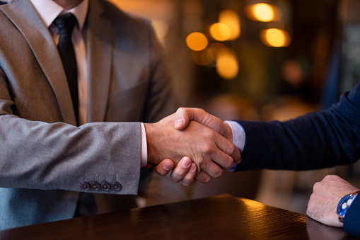 Unrecognizable businessman wearing business suit shaking hands with business partner after successful agreement. Partnership handshake trust concept. Business colleagues handshake.