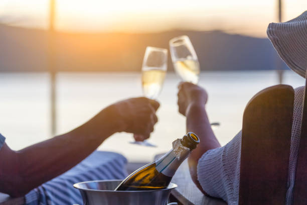 Couple relaxing and drinking champagne on deck chairs on the waterfront. stock photo
