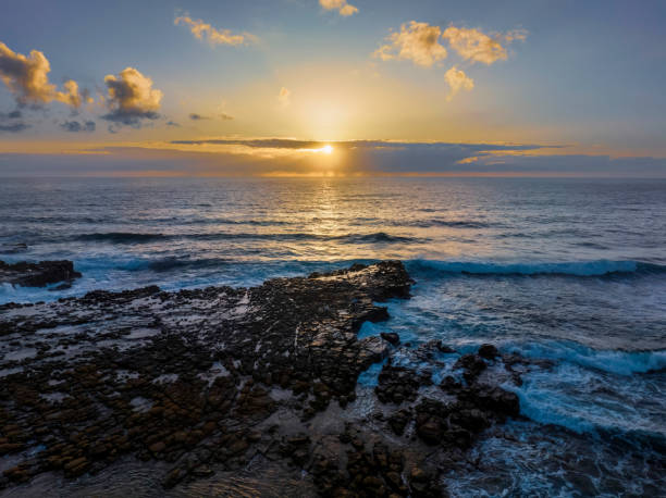 istock Sunrise over the ocean and rock platform 1464255544