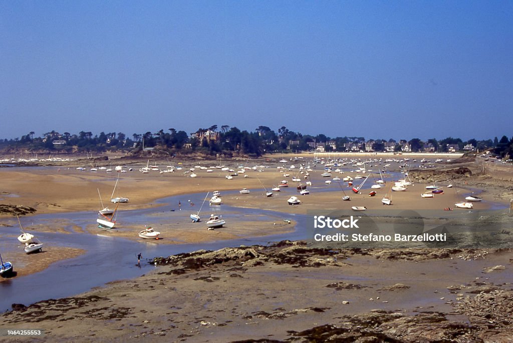 Boats ashore at low tide inBrittany In the estuary of a river on the Breton coast, dozens of dry boats await the return of the tide to float again. Nautical Vessel Stock Photo