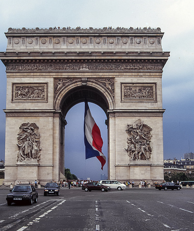 Paris, France - aug 18, 1997: a huge flag with the French colors is waving under the monumental and famous Arc de Triomphe in Paris