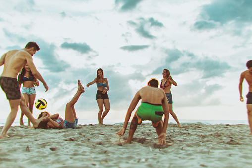 A group of teenagers enjoy a summer day outdoors at sea. The friends play dance and relax on a beach during summer vacation