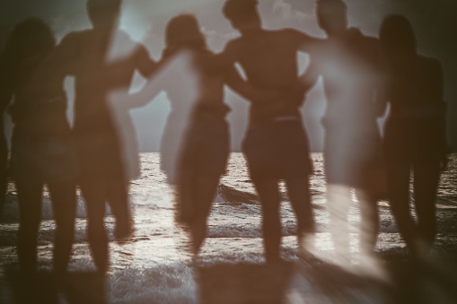 A group of teenagers enjoy a summer day outdoors at sea. The friends play dance and relax on a beach during summer vacation