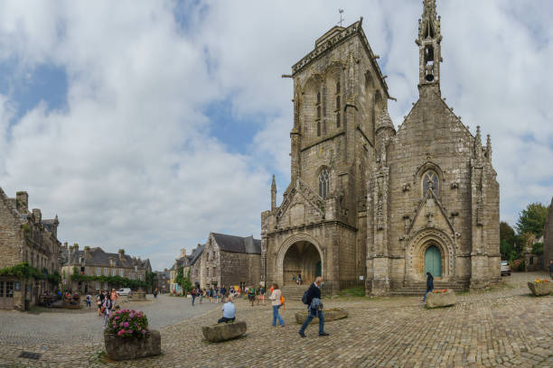 Typical beautiful breton Flamboyant Gothic church named Eglise Saint-Ronan with town square in small medieval village of Locronan, Brittany, France stock photo