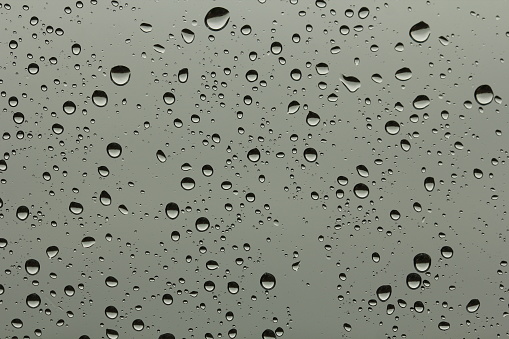 Water drops on window with dark grey sky background