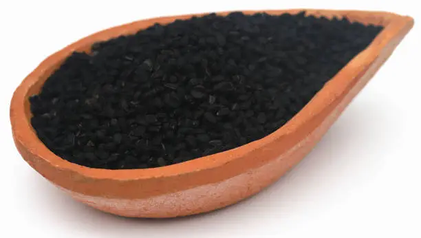 Nigella seeds in bowl over white background