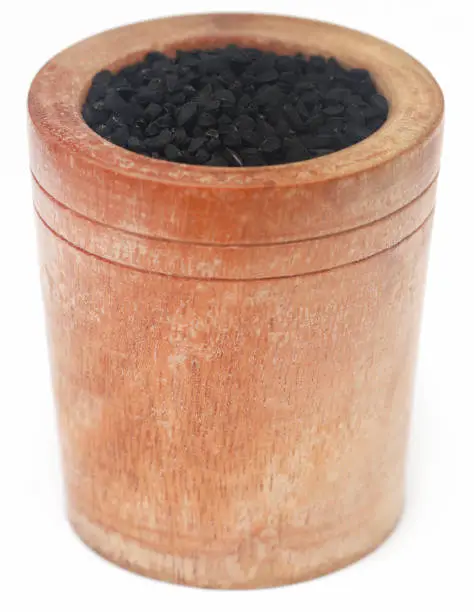 Nigella seeds in bowl over white background