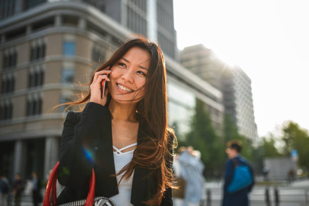 istock Smiling Mid Adult Japanese Female Calling With Her Phone While Going Back Home 1464284679