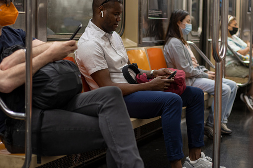 New York, NY, USA - July 8, 2022: Passengers use their mobile phones on a subway train in New York City.