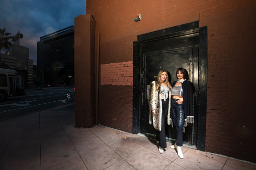 Portrait of two of the members of a rock band standing by the door of a music venue.