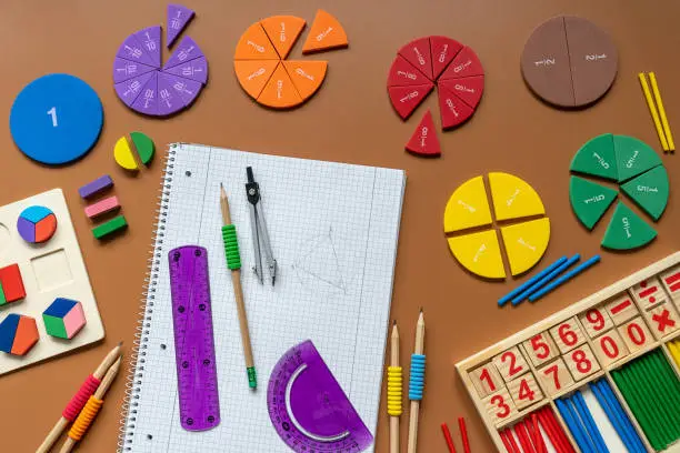 Photo of Fractions, rulers, pencils, notepad on brown background. Set of supplies for mathematics and for school.  Back to school, fun education concept