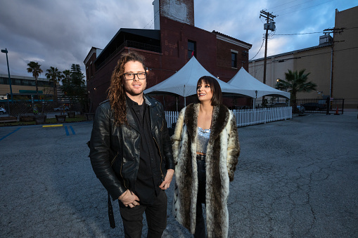 Double portrait of two musicians standing outside a music venue.