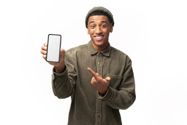 istock Positive confident man pointing at smartphone with white empty display, bragging with application. Indoor studio shot isolated on white 1464308768