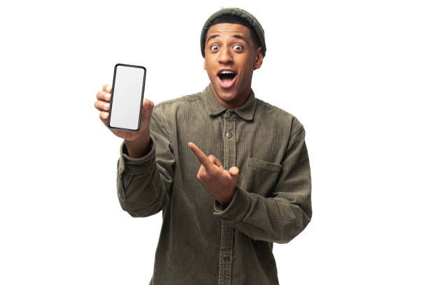 istock Positive confident man pointing at smartphone with white empty display, bragging with application. Indoor studio shot isolated on white 1464308771