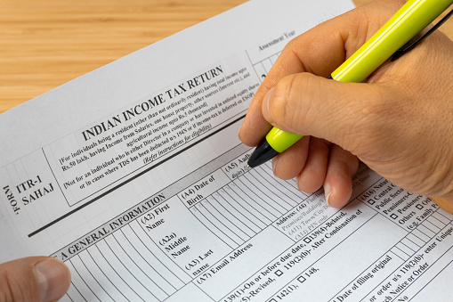 Income tax return in India, ITR1 form and hand with pen of the person completing the returns