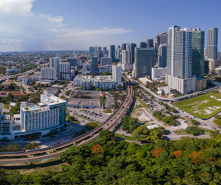 Aerial view of Miami Florida with buildings roads and trees on a sunny day. Beautiful urban landscape with condominiums and skyscrapers on the city skyline against blue sky.