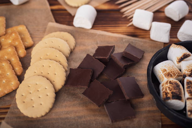 istock marshmallows, chocolate and cookies for making smore on brown background. view from above. copy space 1464314412
